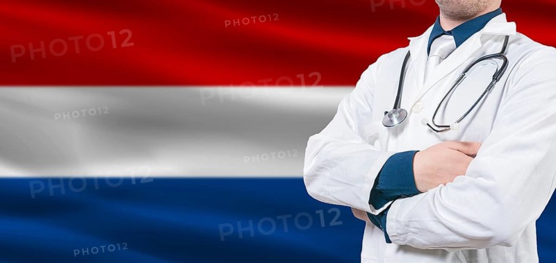Netherlands healthcare concept. Male doctor on Dutch flag. Doctor with crossed arms on Dutch flag