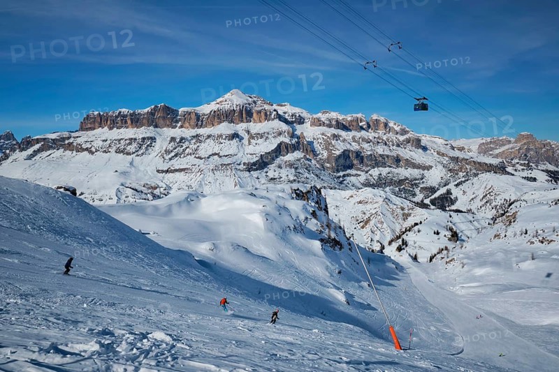 View of a ski resort piste with people skiing in Dolomites in Italy with cable car ski lift. Ski area Arabba. Arabba, Italy