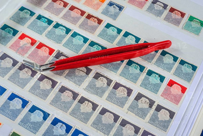 Philately, tweezers on album page with Dutch stamps