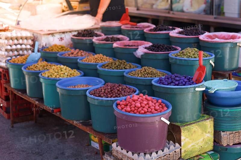 Various colorful olives displayed in buckets at a market stall