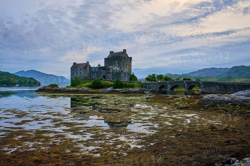 An old castle reflected in calm water, connected by a stone bridge under an evening sky, Eilean Donan Castle, Dornie, Kyle of Lochalsh, Scotland, United Kingdom, Great Britain