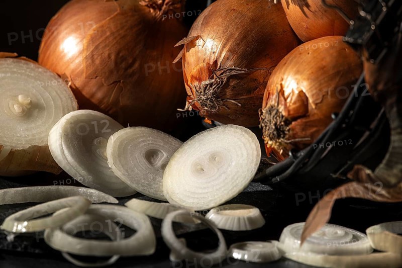 Sliced and whole onions in a basket, warmly lit
