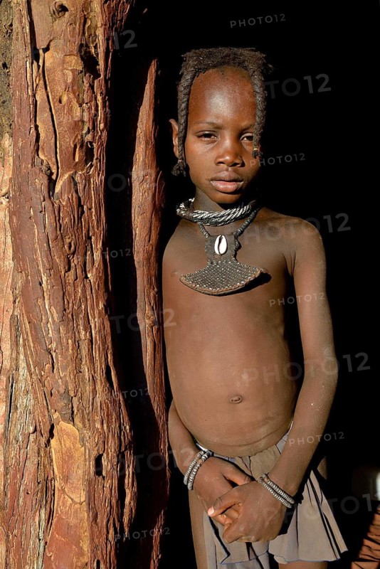 Himba girl standing at the door of her hut, Omohanja, Kaokoland, Kunene, Namibia