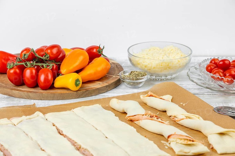 Preparation of pizza sticks with sliced dough next to fresh tomatoes and peppers, pizza