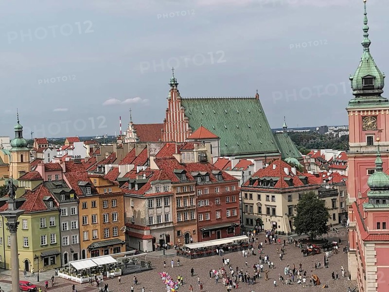 Historic city center with colorful houses and a church, bustling with tourists, Warsaw, Poland