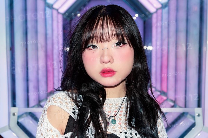 An Asian Gen Z girl enjoys the colorful ambiance of an arcade, highlighting the vibrant, modern setting with neon lights Her expression captures youthful energy and style