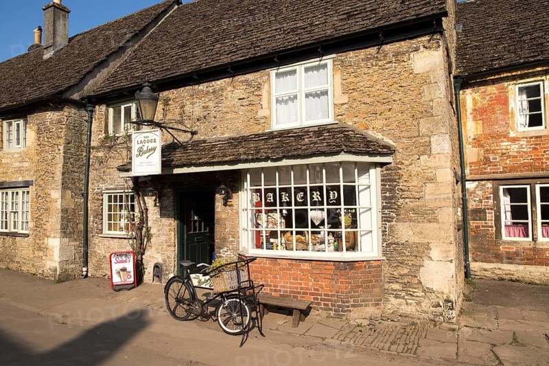 Old bicycle outside the village bakery shop, Lacock, Wiltshire, England, UK
