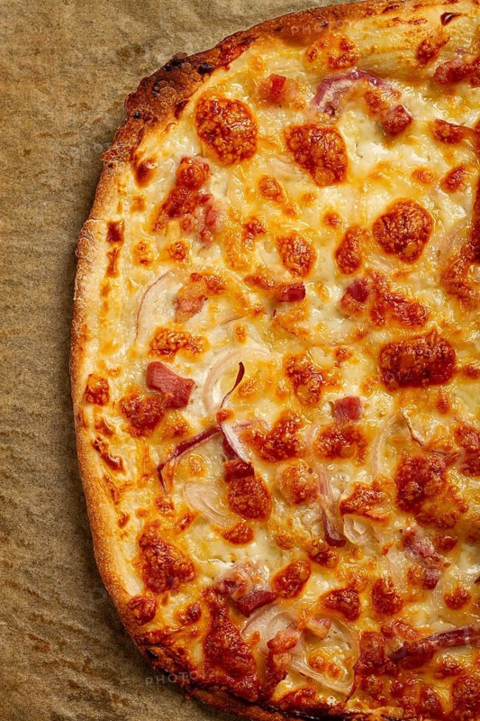 Tart flambe, open pie, rectangular pizza, with cheese and red onion, bacon slices, Alsatian dish, homemade, no people
