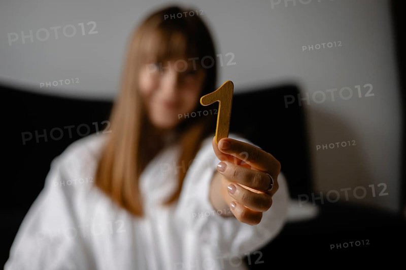 The woman presents a yellow number 1, focusing on it