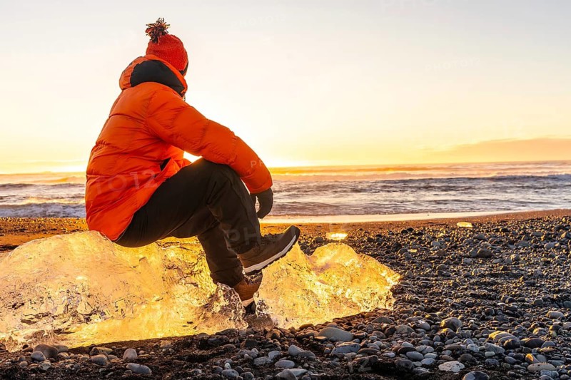 Sitting on a giant chunk of ice at sunrise on Diamond Beach Iceland in winter