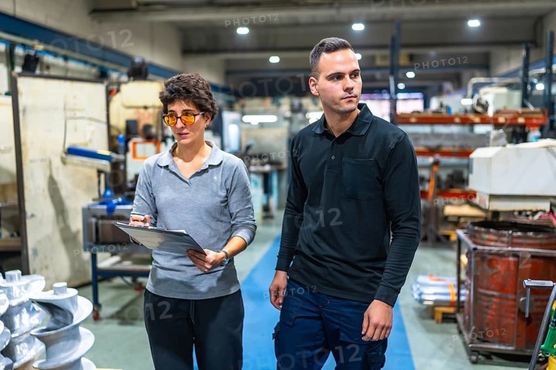 Female manager and male manual worker inspecting a cnc factory walking together and talking