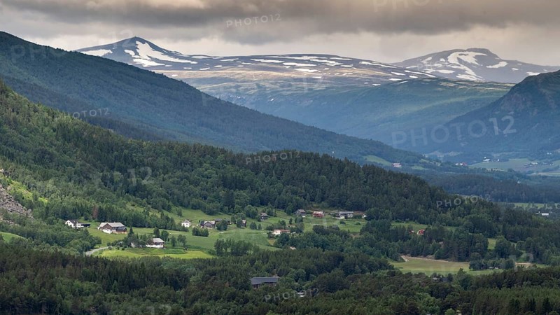 Landscape with houses, farms, mountains, forests and scattered villages under a cloudy sky, Dovrefjell, Upper Gudbrandsdalen, Norway