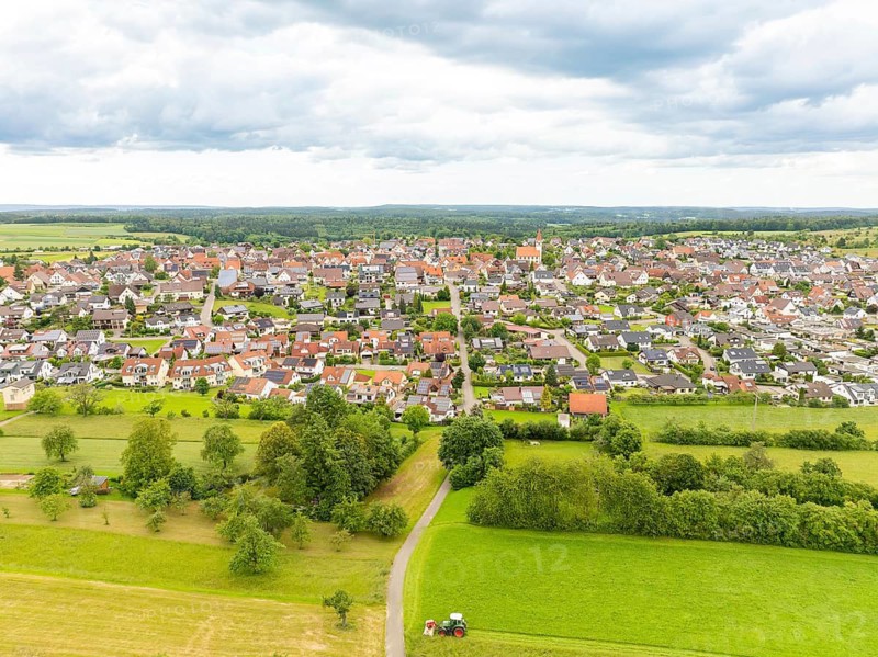 Aerial view of a wide village with red roofs and green meadows, embedded in the landscape under a cloudy sky, Deckenpfronn, Black Forest, Germany