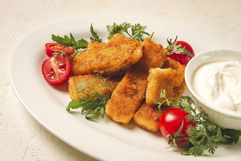 Fried fish nuggets, with white sauce, arugula and cherry, no people