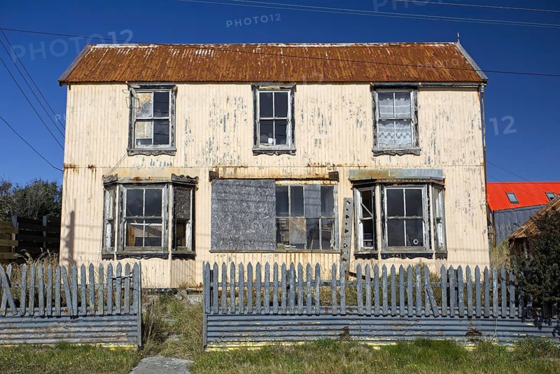 Dilapidated two-storey house with rusty corrugated iron roof, broken and barricaded windows, Stanley, East Falkland, Falkland Islands (UK), British Overseas Territory