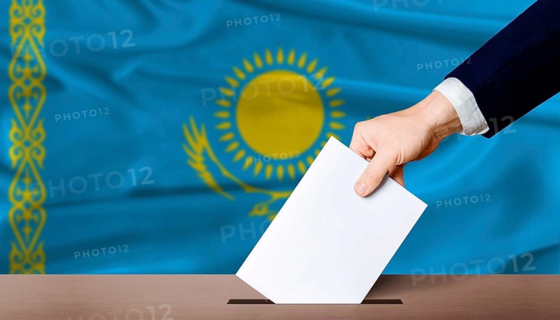 Kazakhstan Parliamentary vote. Hand placing a ballot in ballot box with the Kazakh flag in the background