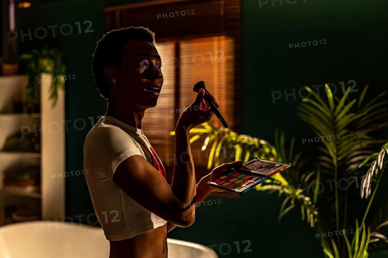 Side view of a latin beauty gay man making up at the evening at home getting ready for a party