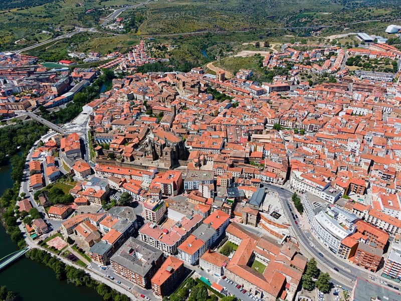Aerial view of a town with red tiled roofs, river, bridge and green trees under a blue sky, aerial view, Plasencia, Jerte River, Cáceres, Caceres, Extremadura, Spain