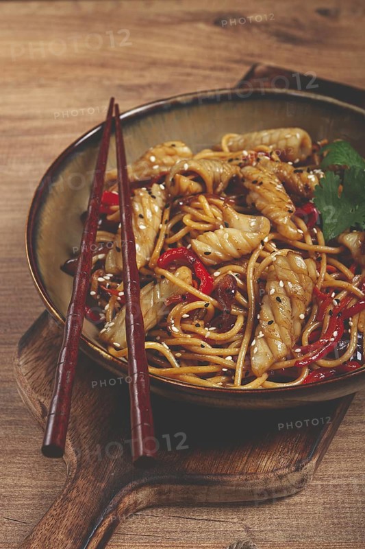 Udon noodles, with squid and vegetables, on a wooden table, homemade, no people