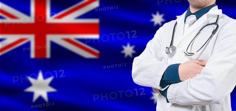Australian Health and Care concept. Professional doctor on Australia flag. Doctor with crossed arms on Australian flag