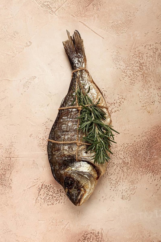 Hot smoked dorado fish, with a sprig of rosemary, tied with a rope, on the table, top view, smoked fish, close-up, no people