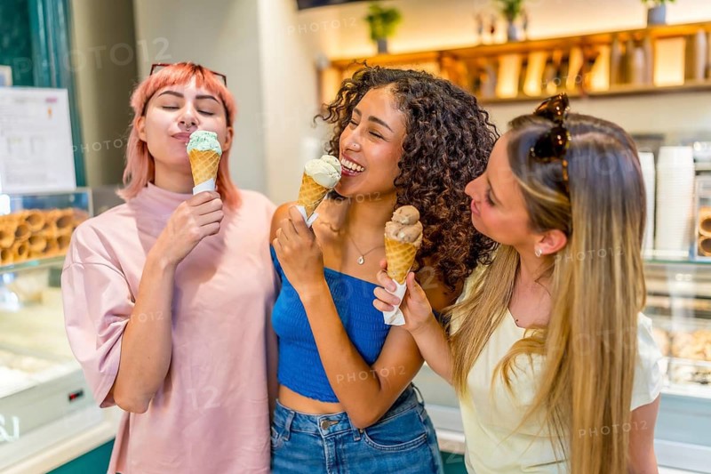 Happy diverse female friends eating delicious ice cream cone standing in a store