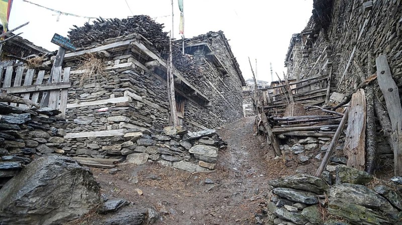 Stone buildings flank a narrow, rocky alley in a mountain village, trekking at Annapurna Circuit, Manang, Nepal