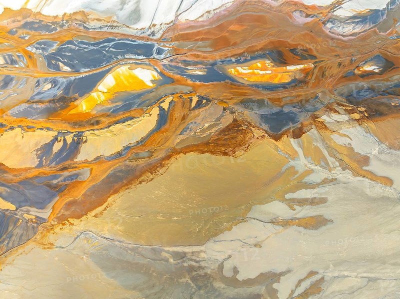 From above, this aerial drone capture showcases a breathtaking view of abstract natural textures, featuring swirling patterns and vibrant, earthy colors