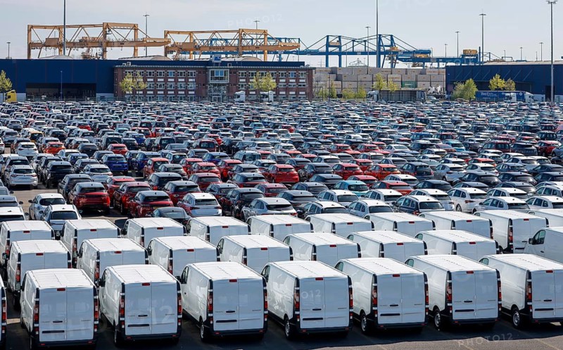 Duisburg, North Rhine-Westphalia, Germany - New cars and vans, car terminal in Duisburg harbour, cranes in the container harbour behind