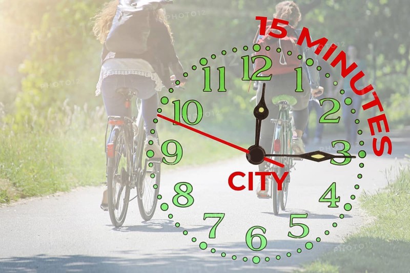 Symbolic image 15-minute city: Cyclist on a cycle path in the countryside and a clock showing fifteen minutes (Composing)