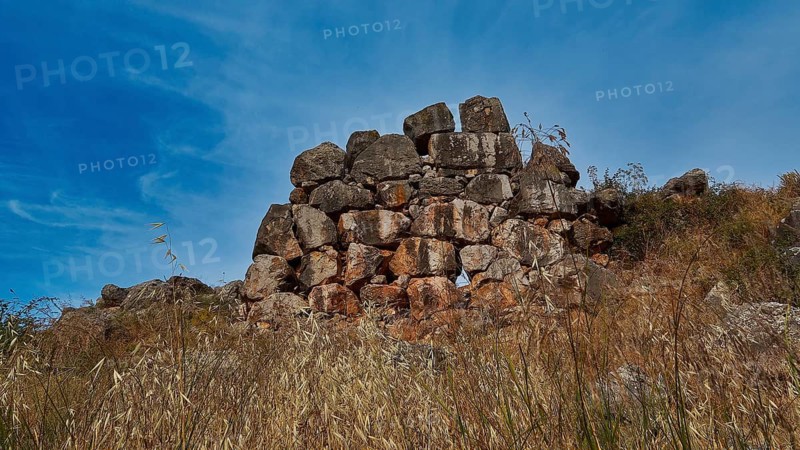 Ancient stone ruins on a grassy hill under blue sky, Tiryns, ancient city in Argolis, Mycenaean, Peloponnese, Greece