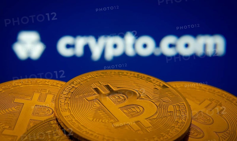 Dhaka, Bangladesh- 26 Aug 2025: Close-up of Bitcoin coins with the Crypto.com logo visible on a screen in the background