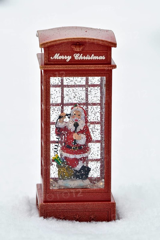 Christmas decoration, Father Christmas standing in snowfall in telephone booth making phone call