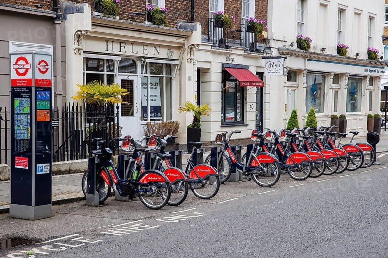 A row of docked public hire bicycles stands outside independent shops on a Marylebone street, London, Eng