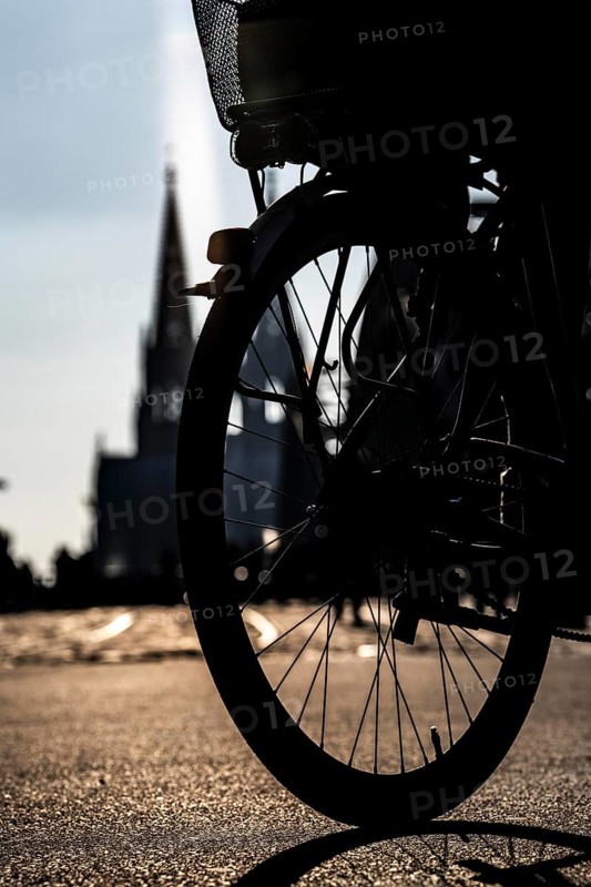 Silhouettes of people in late sunlight, on the Deutz riverbank, right bank of the Rhine, cyclists, on the Rhine promenade, view of Cologne Cathedral and the Hohenzollern railway bridge over the Rhine near Cologne, North Rhine-Westphalia, Germany