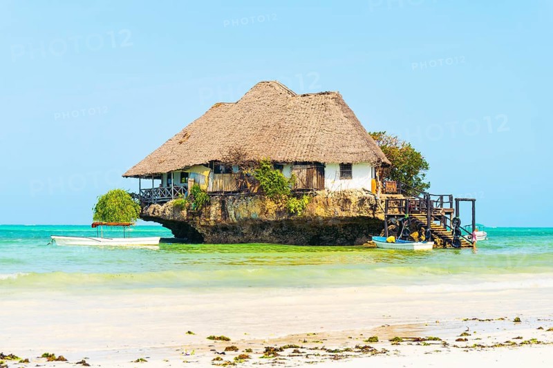 Unique wooden restaurant structure built on coral rock outcrop in turquoise Indian Ocean waters near Michamvi Pingwe beach Zanzibar Tanzania