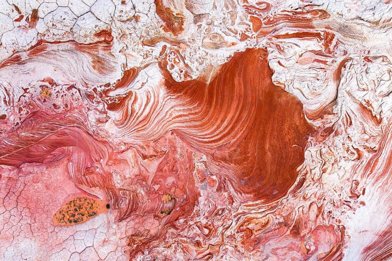 A vibrant close-up of swirling red and white rock formations. The textured patterns