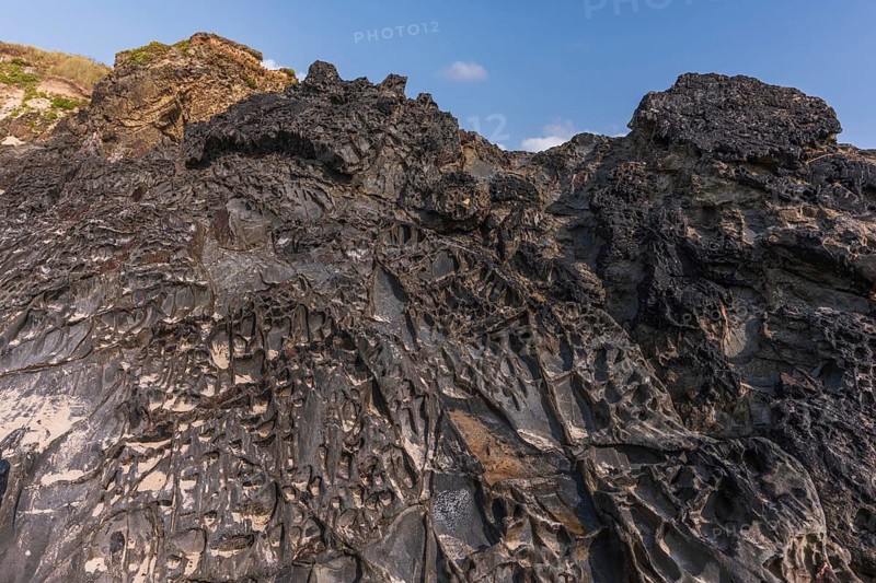 A rock with many holes and caves. Strange shapes in volcanic rock. Crozon, Brittany, Finistere, France