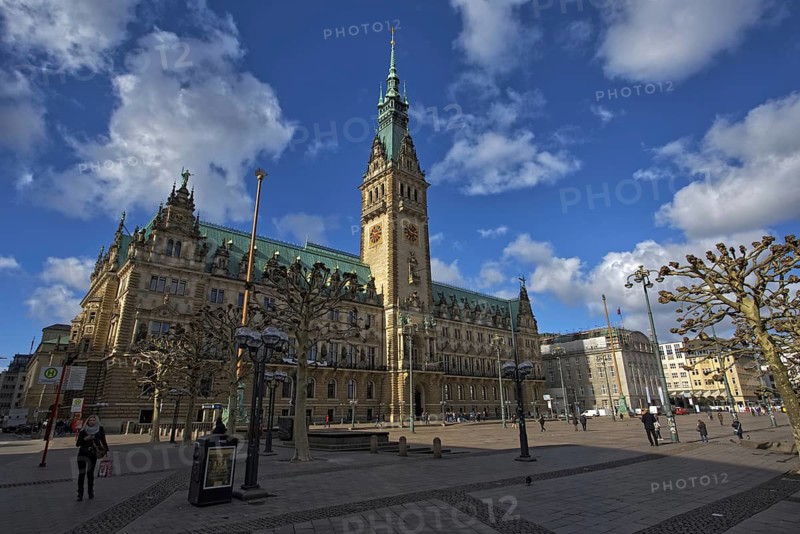 The magnificent Gothic-style Hamburg City Hall rises against a blue sky as numerous people liven up the square, Hamburg, Germany