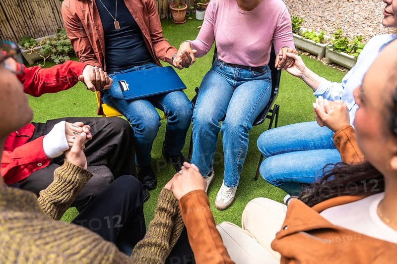 People forming a circle, holding hands, and sharing moments of connection and solidarity during a group therapy session, emphasizing community, empathy, and mental well being