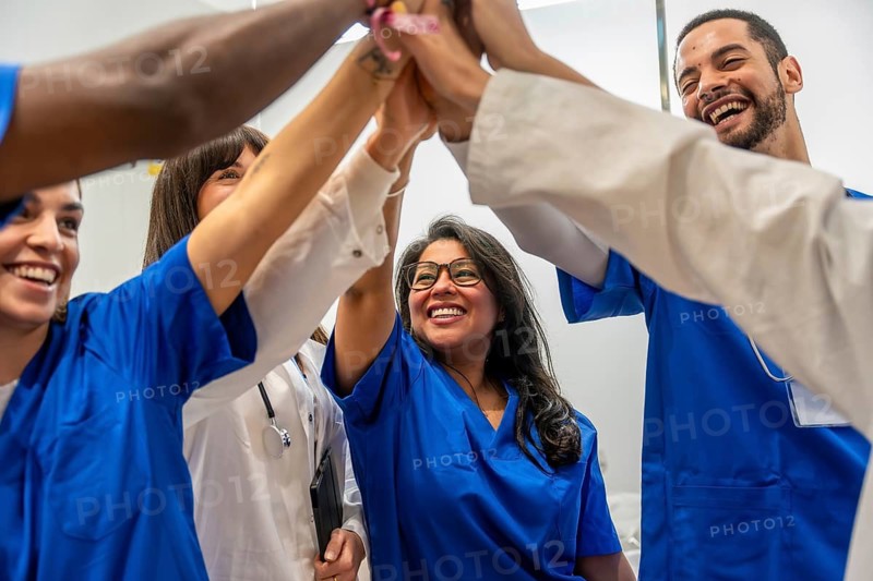 Medical team of doctors and nurses sharing a celebratory high five in a hospital, expressing teamwork, unity, and joyful collaboration after a successful patient outcome