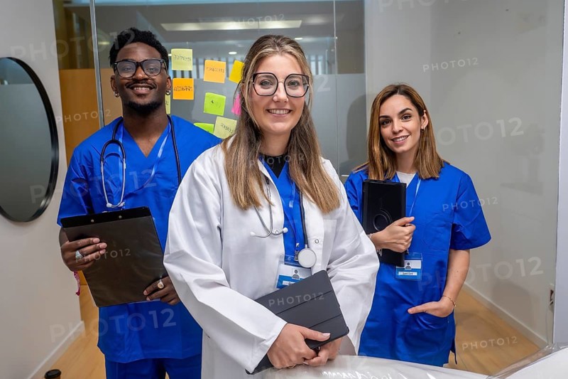 Group of smiling multi ethnic healthcare professionals looking at camera, standing together in a medical office, symbolizing teamwork, innovation, and diverse talent in healthcare