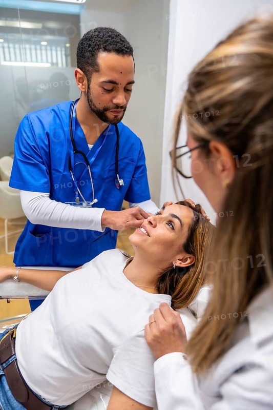 Medical professionals examining a female patient's face and skin for a cosmetic procedure or aesthetic medicine consultation in a modern clinic or hospital setting