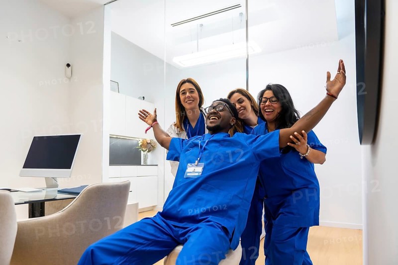 Diverse group of healthcare professionals celebrating a victory or breakthrough in a contemporary clinic, showing joy and teamwork after achieving a positive outcome in patient care or research
