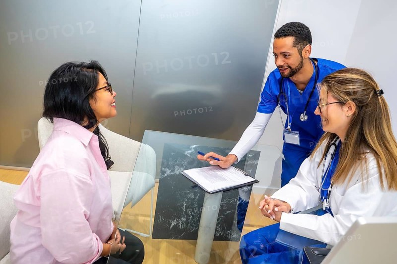 Medical professionals discussing healthcare options and treatment plans with a female patient during a hospital consultation, representing a collaborative approach to health and wellness