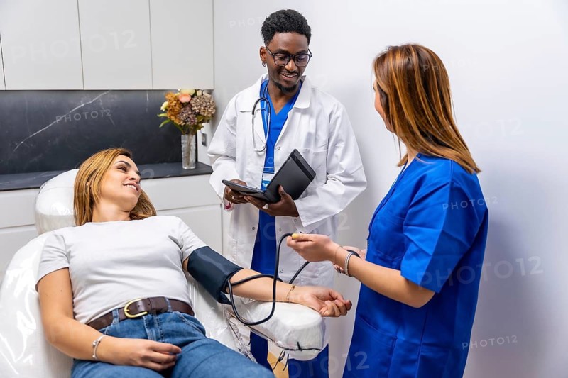 Medical professional team with a doctor and nurse performing a blood pressure check on a female patient in a healthcare center, focusing on routine wellness and preventive care