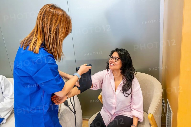 Healthcare professional checking a woman's blood pressure during a routine medical examination, emphasizing preventive care and health monitoring in a modern medical center environment