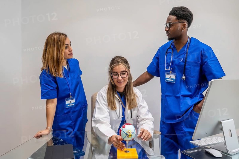 Medical students or young healthcare professionals are gathered around an eye model, actively engaging in a discussion about ophthalmology during a training session in a clinic or hospital setting