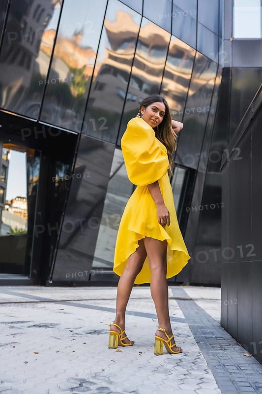 Vertical photo of a beauty model wearing a yellow elegant dress in urban background