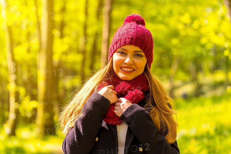 Latin girl with a black jacket, scarf and red woolen hat enjoying in an autumn park, portrait looking at camera
